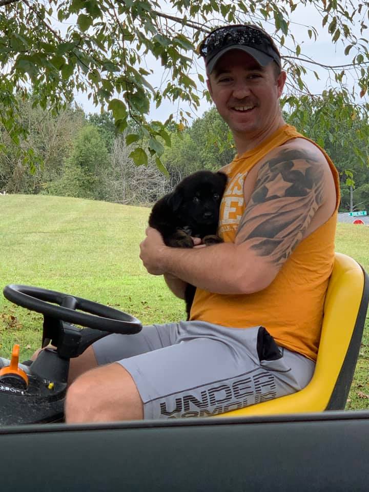 Photo of person with puppy on lawn tractor